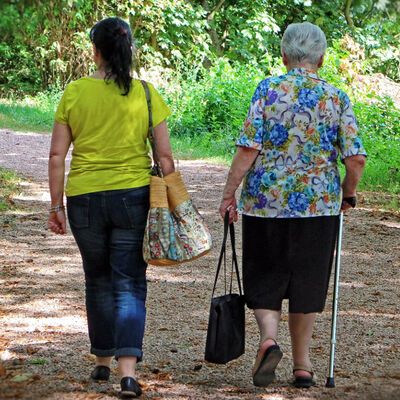 Bild vergrößern: Rückansicht zweier Frauen bei einem Spaziergang auf einem Weg in einem Park.
